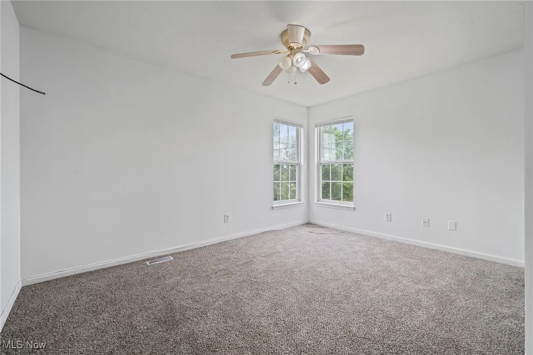 Carpeted empty room featuring baseboards and ceiling fan
