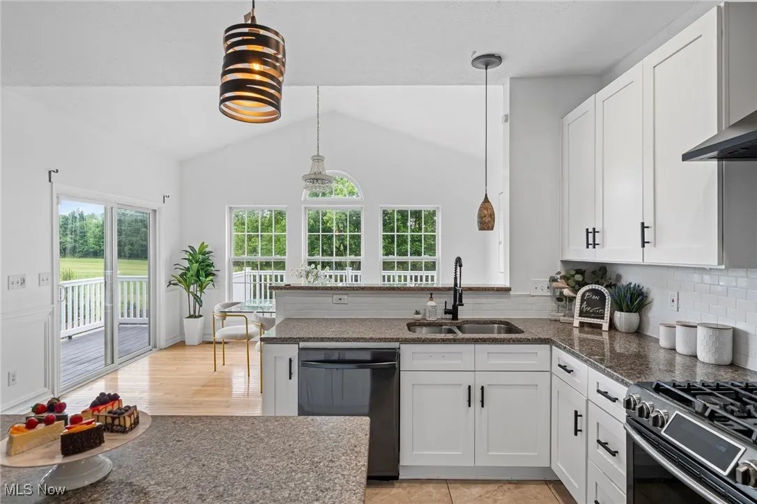 Kitchen featuring dishwasher, a sink, white cabinets, tasteful backsplash, and decorative light fixtures
