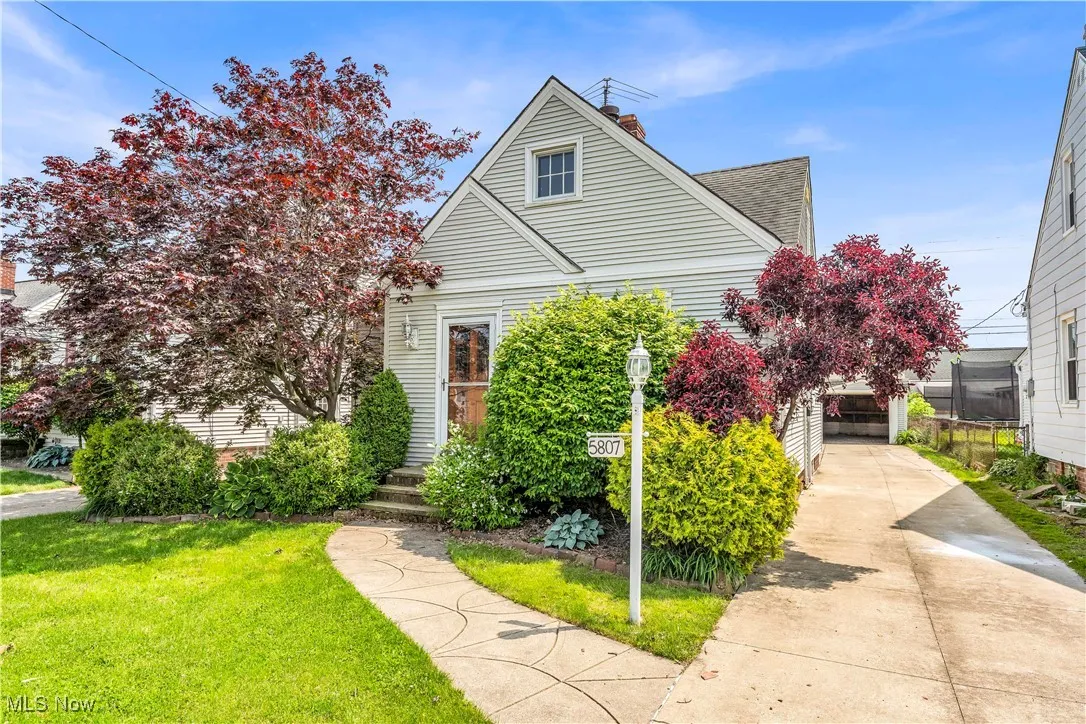View of front of property with a chimney, a front yard, concrete driveway, and roof with shingles