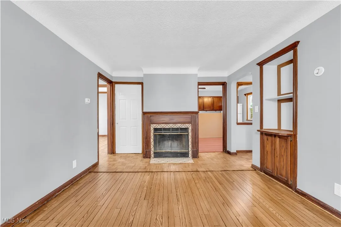 Unfurnished living room featuring baseboards, a fireplace with flush hearth, and light wood-style floors