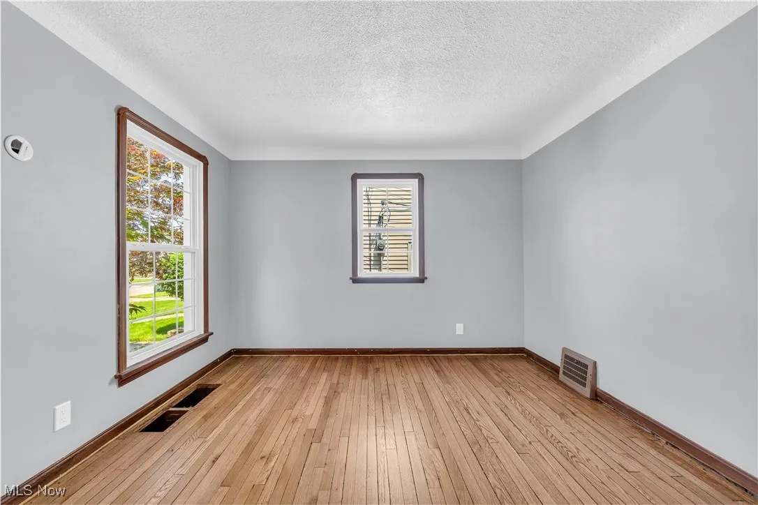 Empty room featuring a textured ceiling, light wood finished floors, and baseboards