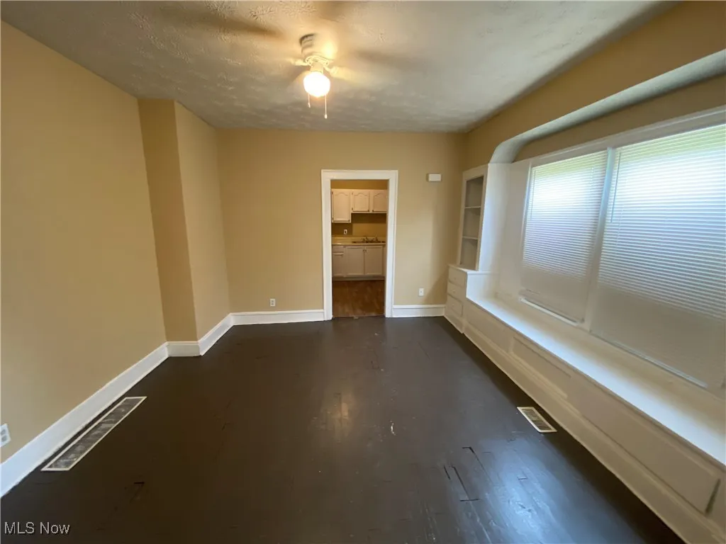 Empty room featuring baseboards, dark wood-style floors, and a textured ceiling