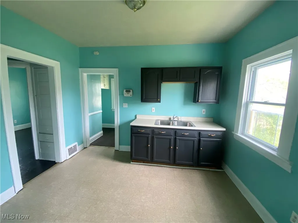 Kitchen featuring a sink, light countertops, and baseboards