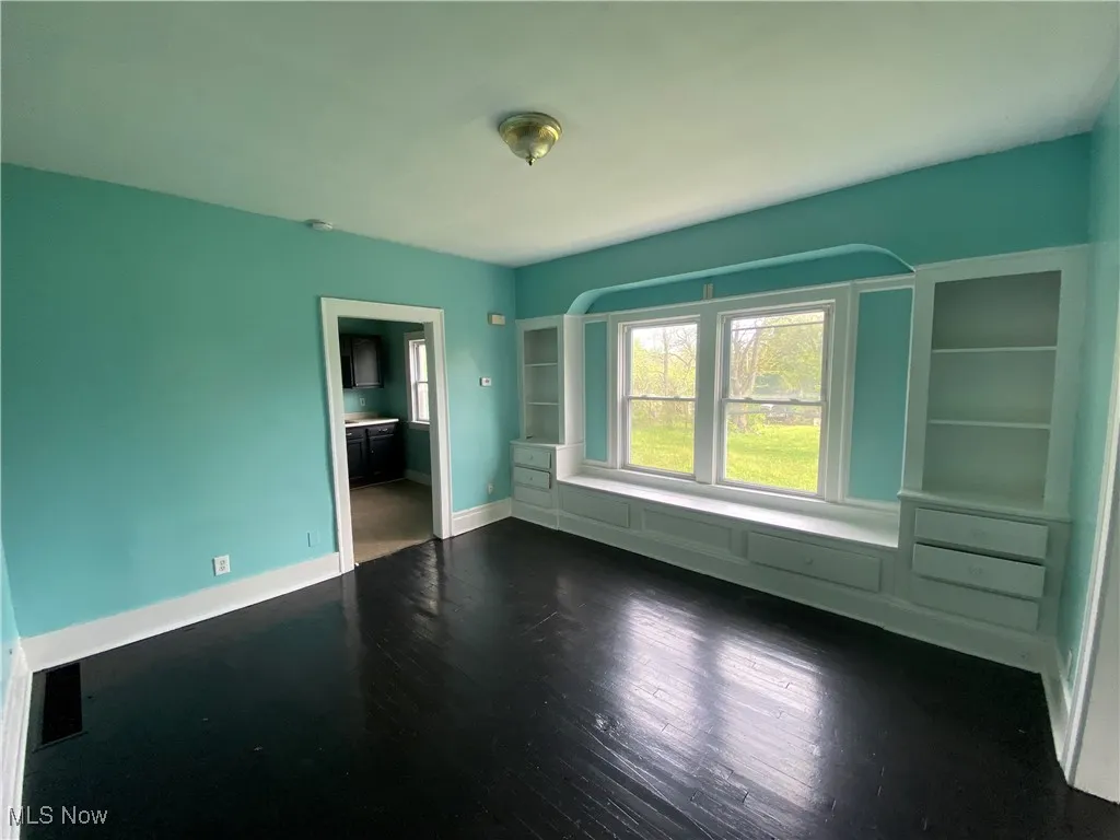 Unfurnished room with dark wood-style flooring and baseboards