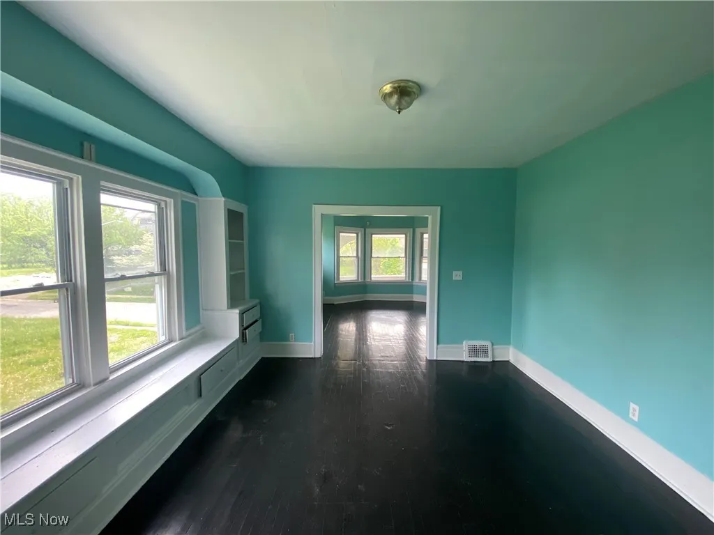 Empty room featuring dark wood-style flooring and baseboards