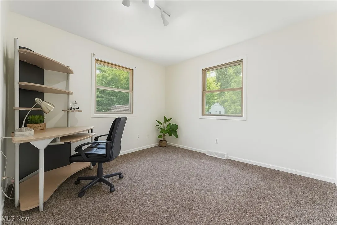 Carpeted office space featuring baseboards and track lighting