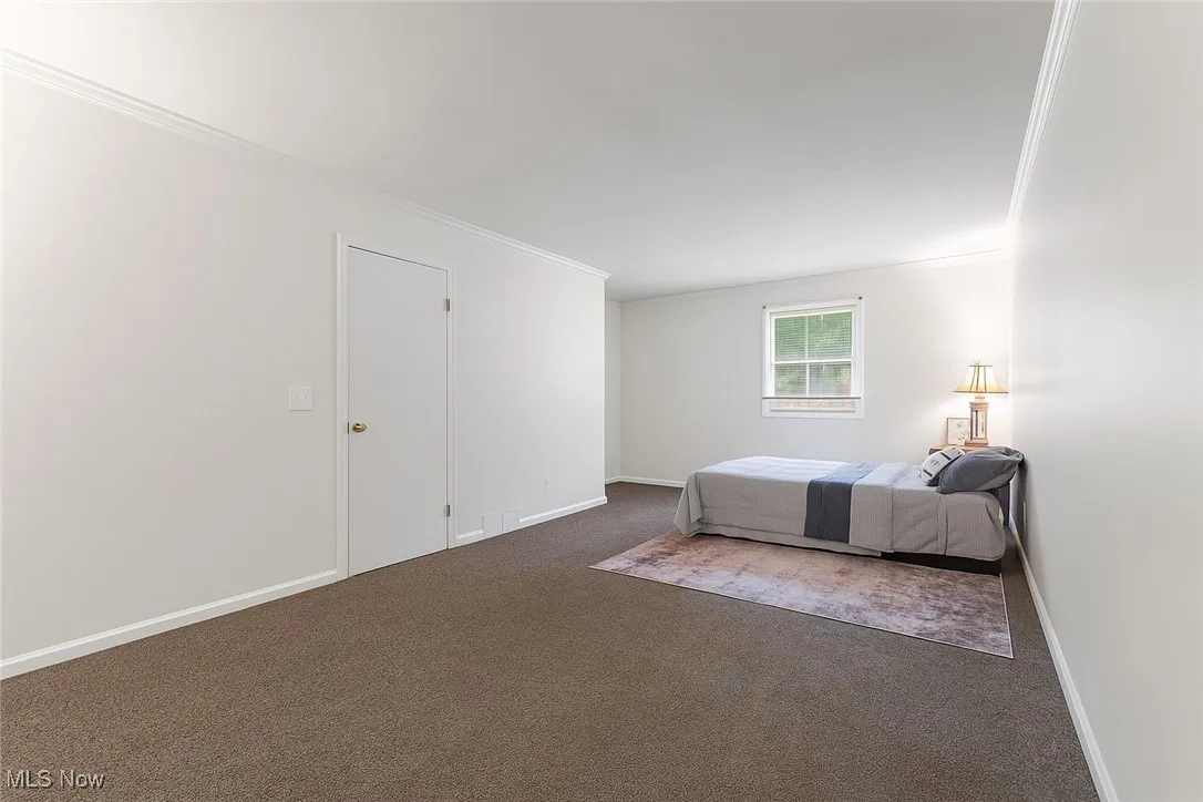 Bedroom with crown molding and dark colored carpet