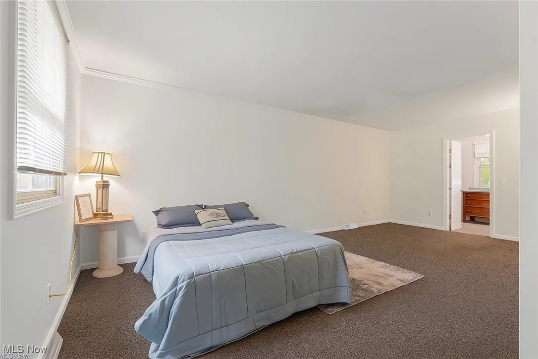 Carpeted bedroom with crown molding and baseboards
