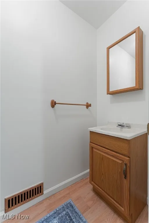Bathroom with vanity, wood finished floors, and baseboards