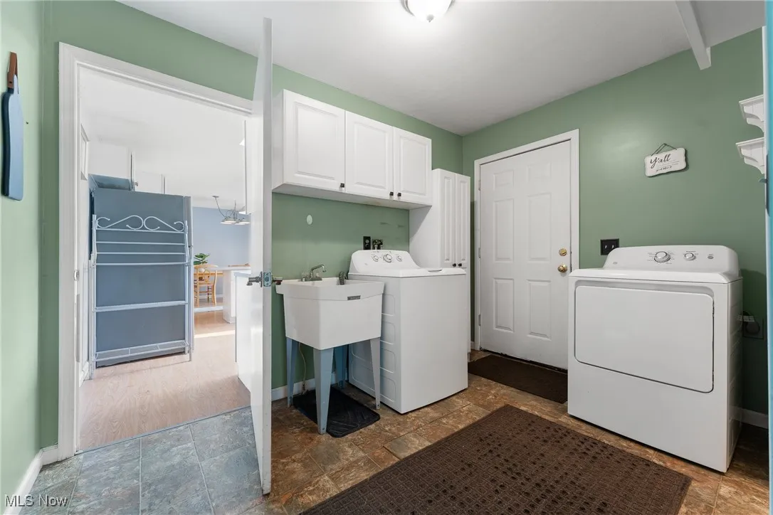 Laundry area with cabinet space, stone finish flooring, and independent washer and dryer