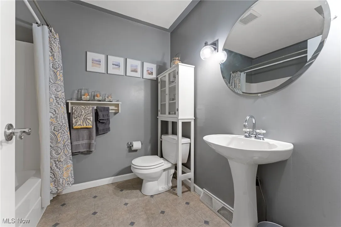 Bathroom with tile patterned floors, toilet, shower / bath combo, and baseboards