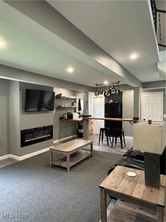 Living room featuring baseboards, a glass covered fireplace, and recessed lighting