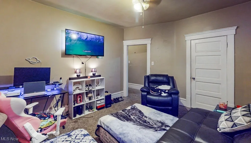 Living room featuring carpet, ceiling fan, and baseboards