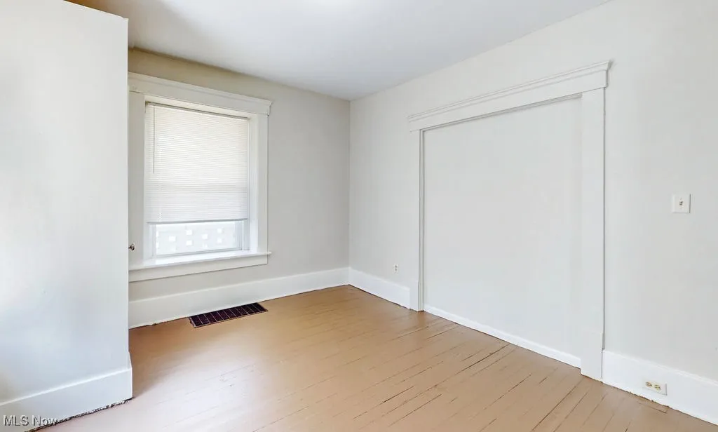 Unfurnished bedroom featuring wood finished floors, baseboards, and a closet