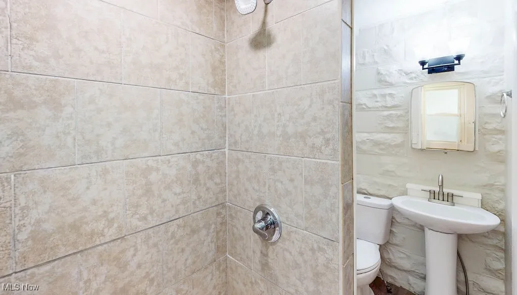 Bathroom featuring tiled shower and toilet