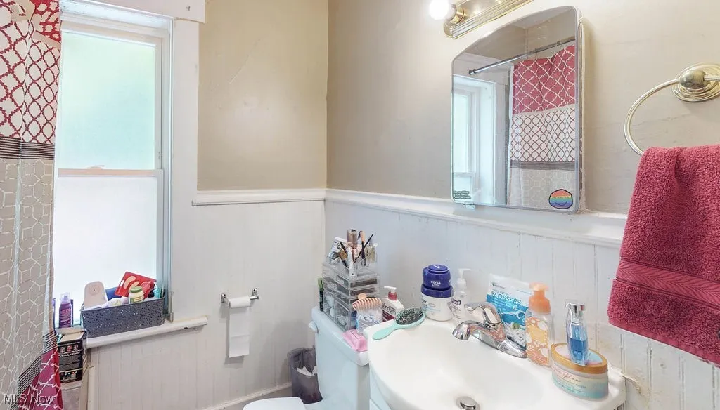 Full bathroom featuring wainscoting, toilet, a shower with shower curtain, and vanity