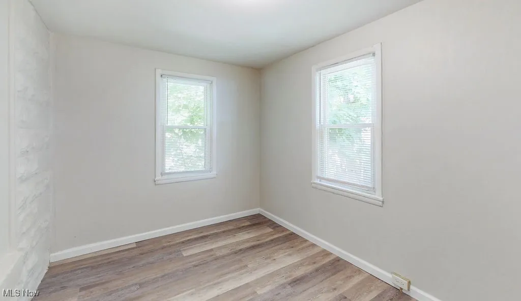 Bedroom featuring healthy amount of natural light, light wood-style floors, and baseboards