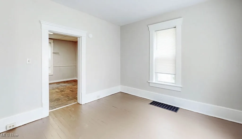 Unfurnished room with wood finished floors and baseboards