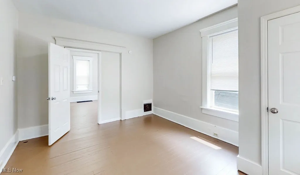 Unfurnished bedroom with wood finished floors and baseboards