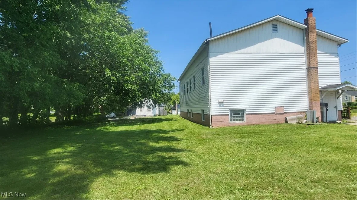 View of side of property featuring a yard and a chimney