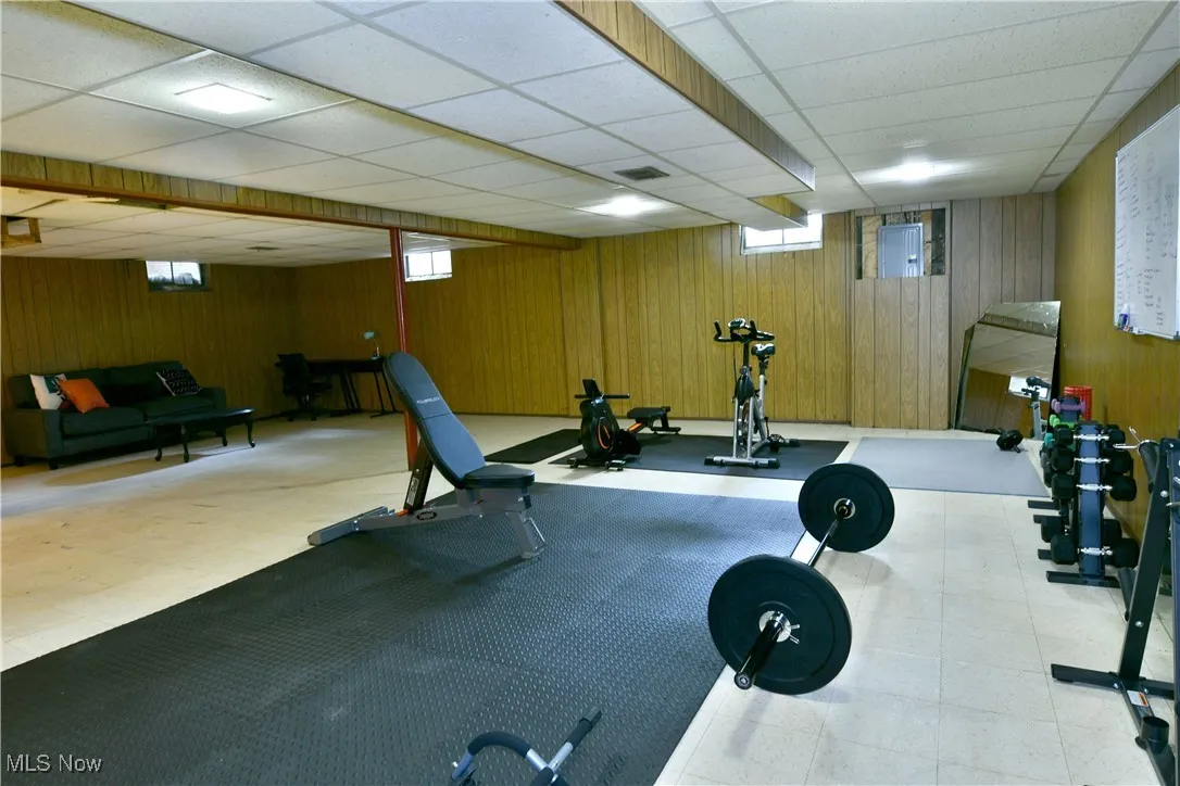 Exercise room featuring wood walls and a paneled ceiling