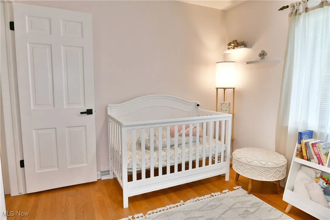 Bedroom with wood finished floors and a crib