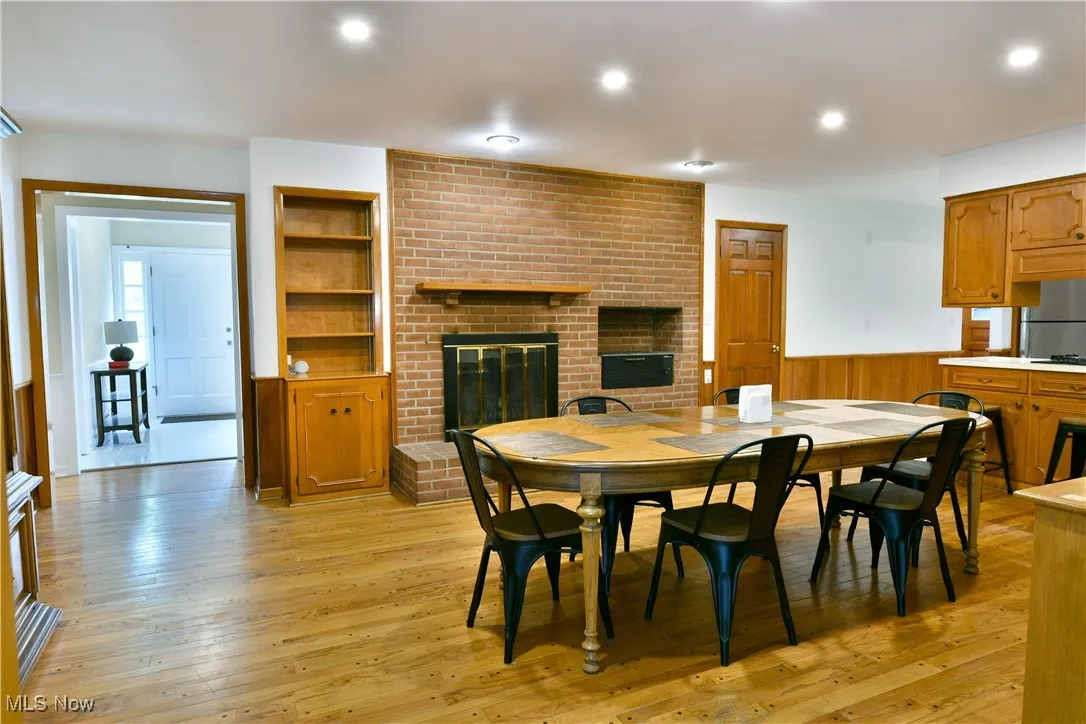 Dining room featuring a fireplace, a wainscoted wall, light wood finished floors, and recessed lighting