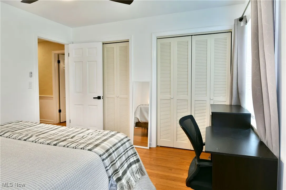 Bedroom featuring two closets, light wood-style flooring, an office area, and ceiling fan