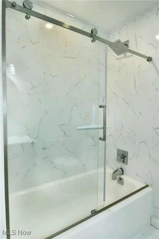 Full bathroom featuring bath / shower combo with glass door