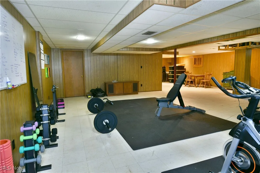Exercise room with wood walls, a drop ceiling, and tile patterned​​‌​​​​‌​​‌‌​‌‌​​​‌‌​‌​‌​‌​​​‌​​ floors