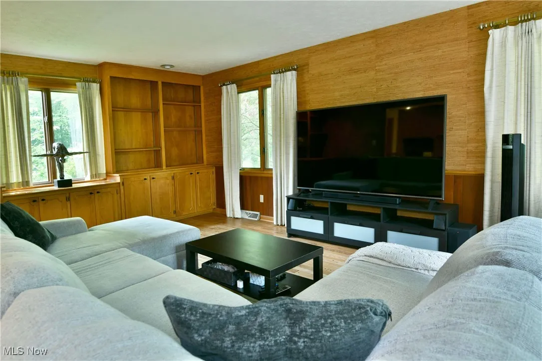 Living area with healthy amount of natural light, wood finished floors, and wood walls