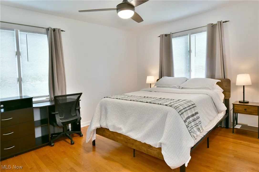 Bedroom with light wood-style flooring, multiple windows, and an office area