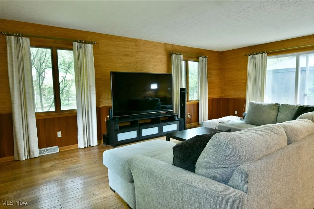 Living area with hardwood / wood-style floors, wood walls, and a textured ceiling