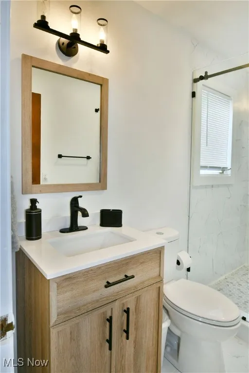 Full bathroom with vanity, a marble finish shower, and toilet