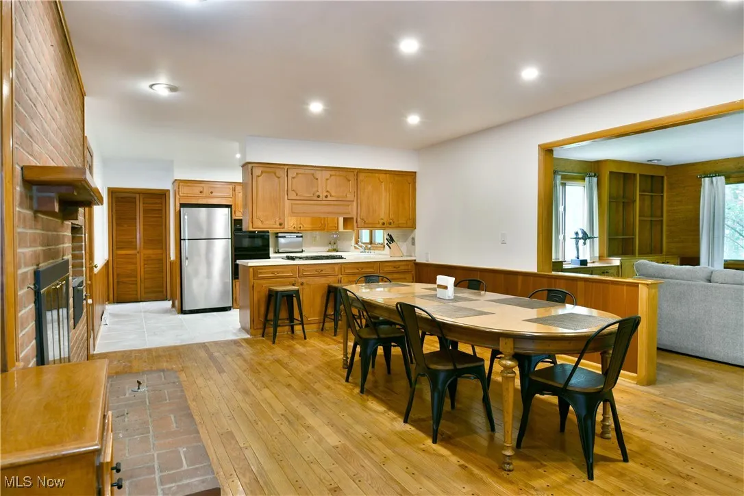 Dining space with a brick fireplace, light wood-style flooring, wainscoting, and recessed lighting