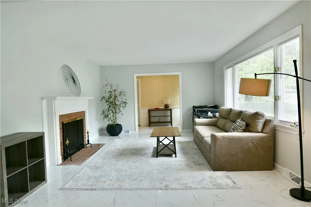 Living room with marble finish floors, a fireplace, and baseboards