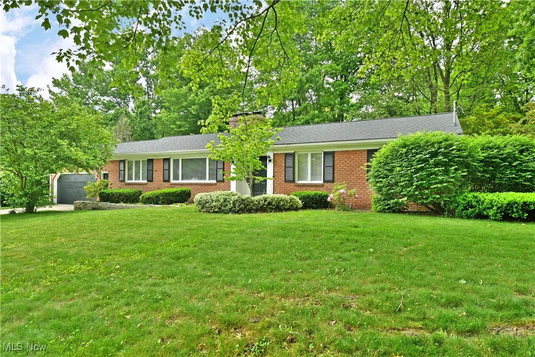 Ranch-style home featuring brick siding, a front lawn, and a chimney
