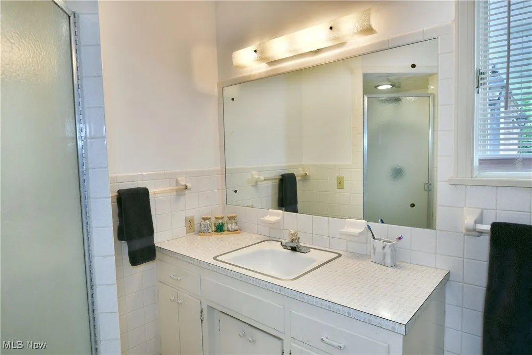 Full bathroom with vanity, a shower stall, and tile walls