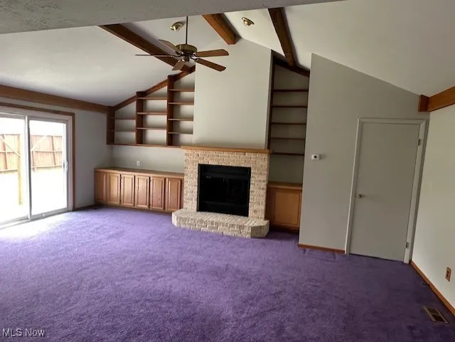 Unfurnished family room with a ceiling fan, carpet flooring, a fireplace, and baseboards