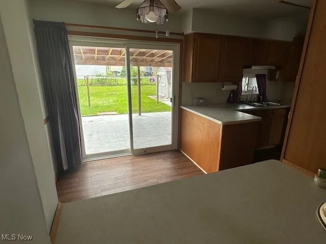 Kitchen with a ceiling fan, brown cabinets, light countertops, wood finished floors, and tasteful backsplash