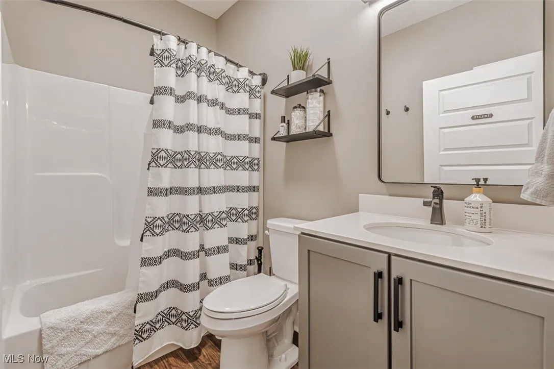 Full bathroom featuring vanity, toilet, shower / bath combo, and wood finished floors