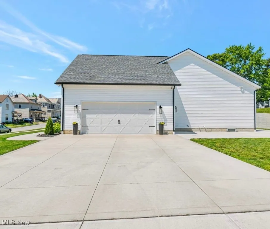 View of home's exterior featuring driveway, a garage, and a shingled roof