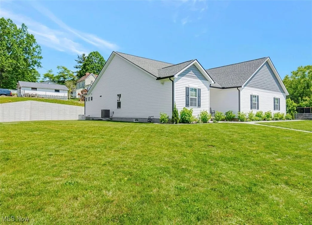 View of side of property featuring a yard and cooling unit
