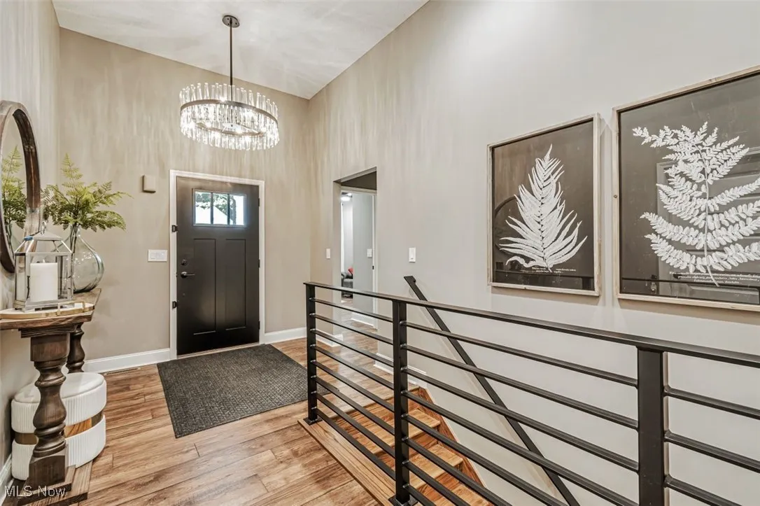 Entryway featuring a high ceiling, wood finished floors, a chandelier, and baseboards