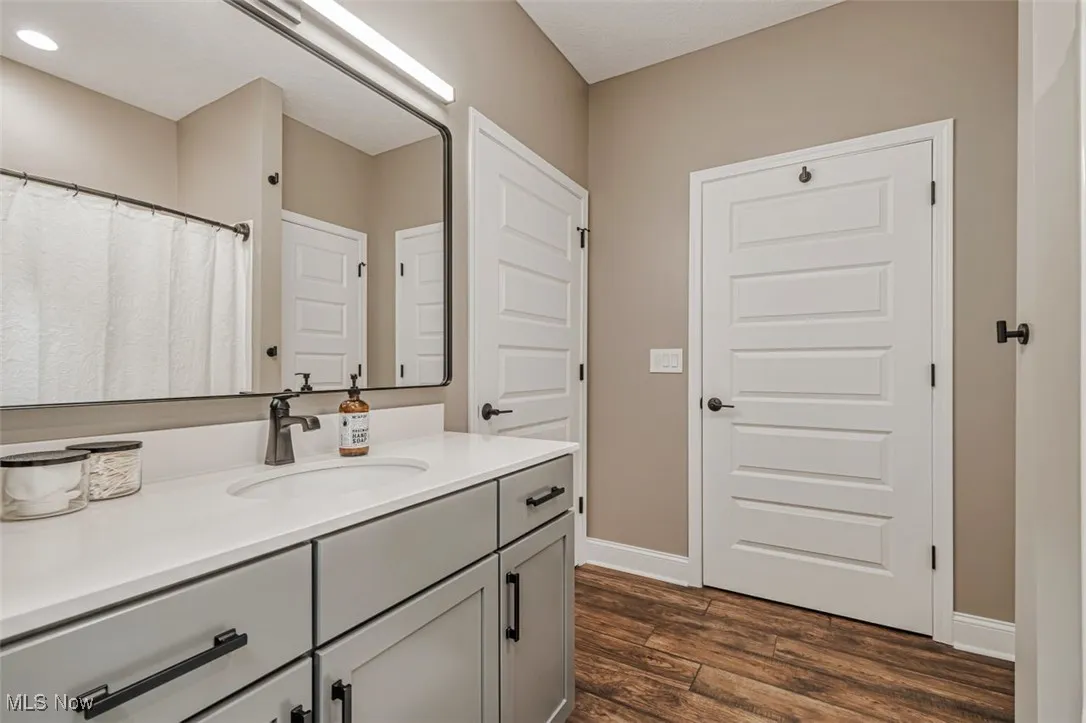 Full bath featuring vanity, wood finished floors, and baseboards