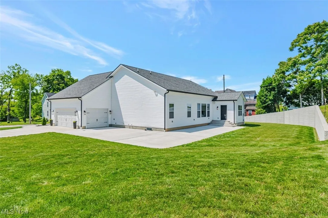 Back of house with an attached garage, entry steps, and concrete driveway
