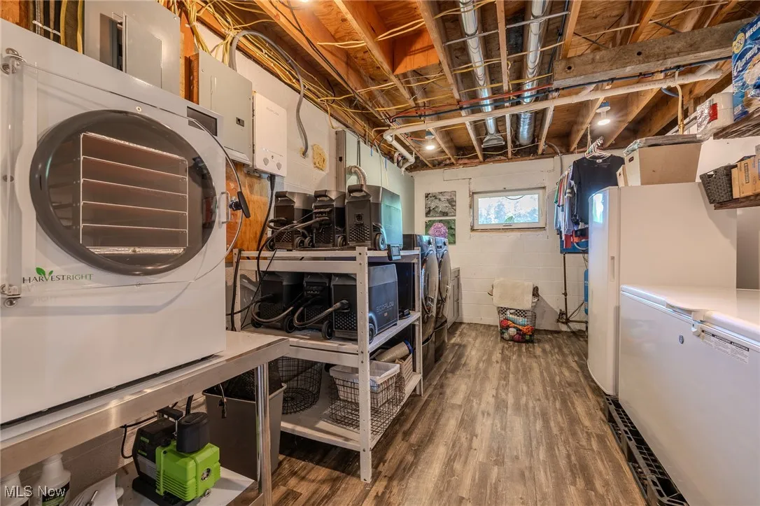 Basement with refrigerator, wood finished floors, electric panel, and freestanding refrigerator