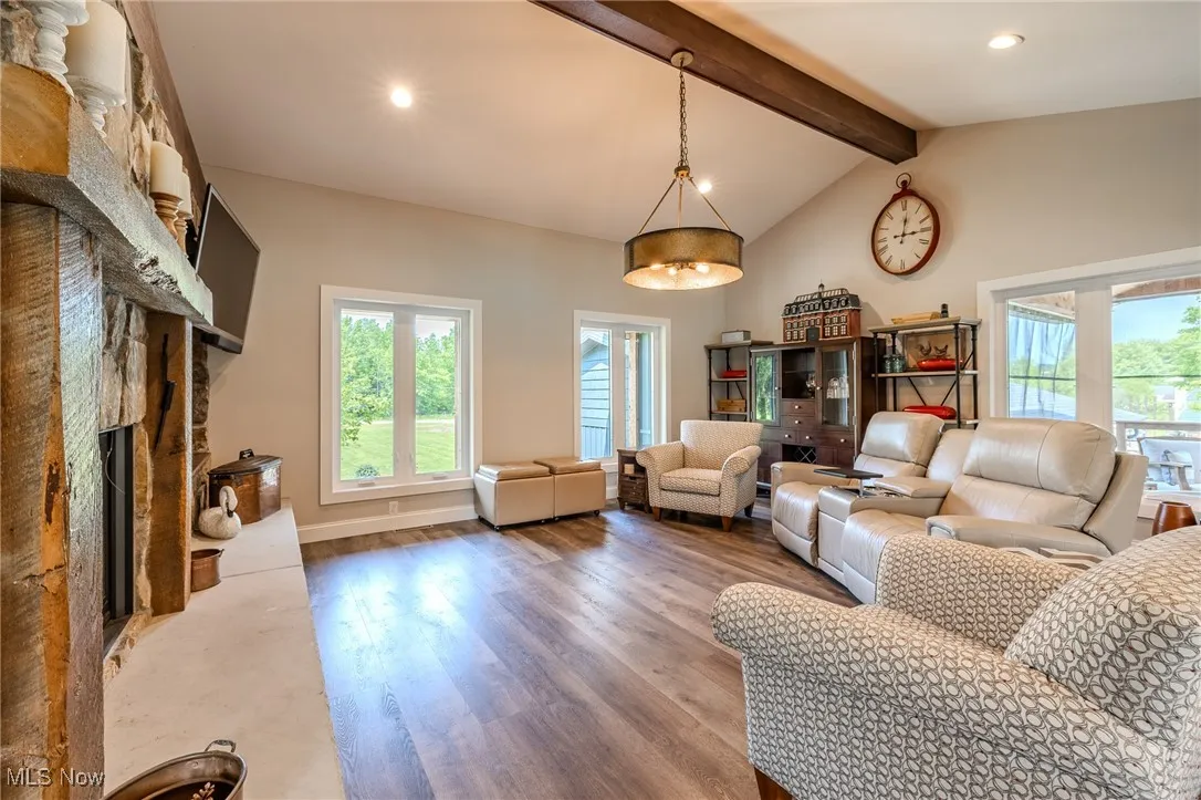 Living room featuring a stone fireplace, wood finished floors, recessed lighting, and baseboards