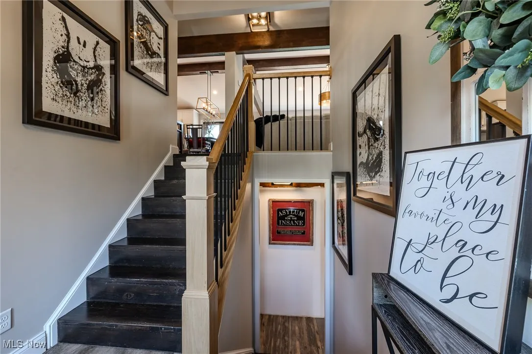 Stairs with wood finished floors and a chandelier