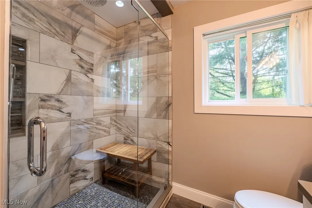 Full bath with a stall shower, toilet, and baseboards